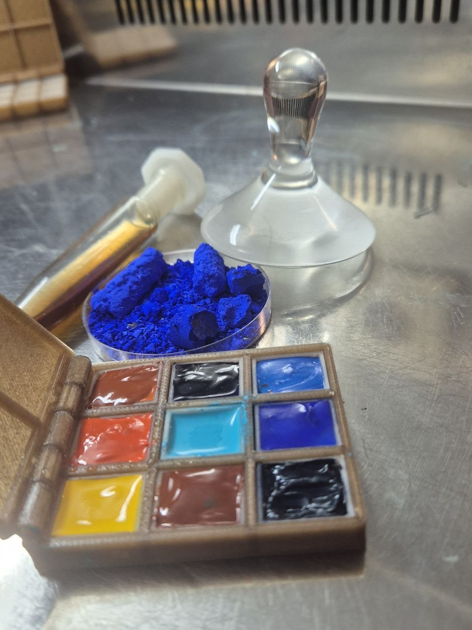 Handmade watercolours in a 3D-printed case next to blue earth pigment in a petri dish